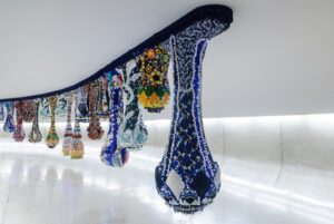 Joana Vasconcelos Instagram - Pela primeira vez, o icónico túnel de Oscar Niemeyer recebe uma intervenção de 47 metros site-specific temporariamente instalada como complemento à exposição Extravagâncias. Foi neste local, simultaneamente de passagem e de encontro, que Joana Vasconcelos visualizou a sua “Cortina do Sonho” que se apresenta como um véu de componentes têxteis, cor e luz, e onde do teto descem 41 módulos em forma de gota de alturas variáveis.

Sendo uma obra desenvolvida em colaboração com a Dior, a “Cortina do Sonho” define o percurso até à Valquíria Miss Dior que lhe serviu de mote. Pondo em foco a ligação entre a moda e o saber fazer manual, a artista plástica interpela diferentes universos criativos, enquanto estabelece um diálogo, único e irrepetível, entre escultura e arquitetura, a partir da criação de Oscar Niemeyer.

Não perca a oportunidade de visitar a exposição até dia 22 de setembro no MON.

💧💧💧

For the first time, Oscar Niemeyer’s iconic tunnel is receiving a 47-metre site-specific intervention temporarily installed as a complement to the Extravagances exhibition. This is the place where Joana Vasconcelos visualised her “Dream Curtain”, a veil of textile components, colour and light, with 41 drop-shaped elements of varying heights descending from the ceiling.

A work developed in collaboration with Dior, the “Dream Curtain” traces the route to the Valkyrie Miss Dior that served as its starting point. Focusing on the link between fashion and manual expertise, the artist explores different creative universes, while establishing a unique and unprecedented dialogue between sculpture and architecture, based on Oscar Niemeyer’s creation.

Don’t miss the chance to visit the exhibition until the 22th of September at MON.

📸 © Marcello Kawase, Cortesia Museu Oscar Niemeyer
@museuoscarniemeyer @julianavosnika @marcpottierart #extravagancias #exposicao #exhibition #joanavasconcelos #escultura #sculpture #joanavasconcelos #artecontemporanea #contemporaryart #art #arte