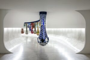 Joana Vasconcelos Instagram - Pela primeira vez, o icónico túnel de Oscar Niemeyer recebe uma intervenção de 47 metros site-specific temporariamente instalada como complemento à exposição Extravagâncias. Foi neste local, simultaneamente de passagem e de encontro, que Joana Vasconcelos visualizou a sua “Cortina do Sonho” que se apresenta como um véu de componentes têxteis, cor e luz, e onde do teto descem 41 módulos em forma de gota de alturas variáveis.

Sendo uma obra desenvolvida em colaboração com a Dior, a “Cortina do Sonho” define o percurso até à Valquíria Miss Dior que lhe serviu de mote. Pondo em foco a ligação entre a moda e o saber fazer manual, a artista plástica interpela diferentes universos criativos, enquanto estabelece um diálogo, único e irrepetível, entre escultura e arquitetura, a partir da criação de Oscar Niemeyer.

Não perca a oportunidade de visitar a exposição até dia 22 de setembro no MON.

💧💧💧

For the first time, Oscar Niemeyer’s iconic tunnel is receiving a 47-metre site-specific intervention temporarily installed as a complement to the Extravagances exhibition. This is the place where Joana Vasconcelos visualised her “Dream Curtain”, a veil of textile components, colour and light, with 41 drop-shaped elements of varying heights descending from the ceiling.

A work developed in collaboration with Dior, the “Dream Curtain” traces the route to the Valkyrie Miss Dior that served as its starting point. Focusing on the link between fashion and manual expertise, the artist explores different creative universes, while establishing a unique and unprecedented dialogue between sculpture and architecture, based on Oscar Niemeyer’s creation.

Don’t miss the chance to visit the exhibition until the 22th of September at MON.

📸 © Marcello Kawase, Cortesia Museu Oscar Niemeyer
@museuoscarniemeyer @julianavosnika @marcpottierart #extravagancias #exposicao #exhibition #joanavasconcelos #escultura #sculpture #joanavasconcelos #artecontemporanea #contemporaryart #art #arte