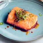 Judy Joo Instagram - Delighted my Green Chilli Glazed Salmon recipe has been featured in @cityamtravel! This dish is packed with a wonderful blend of spicy, sweet, and umami flavours. Here's a brief run-down for you to have a go at home: 1️⃣ Glaze: Gently fry finely chopped garlic and jalapeños in vegetable oil until softened. Mix together soy sauce, brown sugar, and rice wine vinegar. Add to the pan, stir well, and simmer until reduced by half. Finish with a drizzle of sesame oil. 2️⃣ Spring Onion Salad: For the dressing, combine soy sauce, rice wine vinegar, gochugaru (Korean chilli flakes), roasted sesame oil, sesame seeds, and sugar. Cut spring onions into thin strips and immerse in ice-cold water until they crisp up. Toss in the dressing. 3️⃣ Salmon: Heat oil in a pan and fry the salmon fillets until golden brown and cooked to your preference. Arrange salmon on plates, spoon over the glaze, and garnish with the Spring Onion Salad and green chilli slices. Add a pinch of silgochu for an extra kick. Serve with yuja pickles and a side of cooked rice. Enjoy your meal! 🍴 What recipe would you like to see next? Let me know in the comments! And don't forget to visit my website for more delicious recipes. For the full recipe and article, head over to #CityAM. Don't forget to share your culinary creations with us using #GreenChilliGlazedSalmon. Happy cooking! 🍳 • • • • • #koreanfood #salmon #chef #cheflife #chefsofinstagram #cook #cooking #chefs #fish #truecooks #ChefLife #Foodie #FoodPorn #InstaFood #Foodstagram #ChefsofInstagram #FoodPhotography #FoodGasm #FoodLover #FoodBlog #FoodPassion #FoodArt #FoodInspiration #FoodieLife #Cooking #Gourmet #FoodCulture #FoodieGram