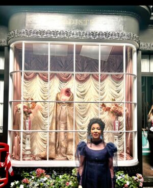 Kathryn Drysdale Instagram - Going to answer some of your questions re Gen here .
1. Why did her shop look different in part 2 season 3 ? 
Thanks to Pen helping boost her business  she upgraded and got a new shop . See before and after 
2.How does she make so many dresses so quickly ?
She has a team of seamstresses who work in the back or from home . She designs the dresses but doesn’t make them all 
3. Why does she always wear the same / similar dress ?The creatives wanted Gen to be have  like a Chanel / Steve jobs / Karl lagerfeld type vibe . Also her job is to make the Ton feel beautiful never to steal the spotlight herself . Sometimes modistes of the time did show off their creations but Genevieve prefers to keep it simple. Her hair in S3 is also always loosely tied up as if in a rush .
4. What happened to her accent in season 3 ? All throughout the 3 seasons Gen actually speaks in her own accent ( london) with people she trusts and when not at work and if she does speak in her accent at work it is usually a whisper or to the side . The French accent is put on to impress the clients who favour Parisian designers . Marina catches her out in season 1 and the first time we see her speaking in her own accent is with Sienna , then Benedict in the club 💙🧵🧵🧵 @bridgertonnetflix @shondaland #bridgerton