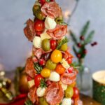 Laura Vitale Instagram - Buongiorno!!!!! See one thing about me is, imma have antipasti at every table 😂 last year they were in the shape of a wreath and this year as Christmas tree!! No recipe obviously just a foam tree wrapped well with plastic wrap and then stab a ton of toothpicks (I find it easier to break them in half) pierce them all around and then attach whatever your heart desires to it. Stay away from oily things as it would make this so messy but it’s just such a show stopper especially if you wanted to make it as a centerpiece to a big charcuterie board. I just love itttt!!!