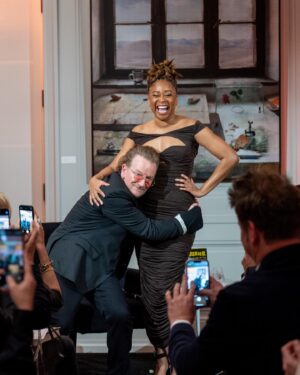 Phoebe Robinson Instagram - When I was asked to interview my friend/mentor Bono at a private book party (hosted by @Bloombergdotorg) celebrating his NYT memoir “Surrender,” I thot to myself, “In my book club, we all getting half chubs,” hence me serving body-ody-ody in a Hershey’s chocolate bar 🍫 wrapping. Jokes aside, this was legit one of the best days of my life.
⠀
Like thirteen year old me would’ve geeked over the opportunity and also fluffed out her Civil Rights era banyang. Seriously, when I was younger I looked I could’ve been in what was originally the Little Rock Ten, but alas I missed it all because I overslept the night before, so Nine it was! ANYWAY! The point is sometimes you dream of and hope for and manifest certain things, but the universe has a way of surprising you with even more when you surrender to it.
⠀
To kiki with a person whose music and philanthropy has meant so much to my life was a dream come true. To hear the way he speaks of and writes about Ali, his wife of 40  years moved me to tears. The way his band mates - Edge, Adam, & Larry - have bettered him in ways that he’s long known and ways he’s still discovering is touching without being overly sentimental. And to watch him take his passions seriously in one breath and then also take the piss out of himself the next is a masterclass in authenticity. He’s a thoroughly self-possessed person, which is probably the most beautiful thing about him.
⠀
So thanks, B, for the pleasure of your friendship, the gift of your generosity, and welcoming me deeper into the @red family by having me join the Advisory Board (I know B said Creative Council, but it’s the Advisory Board). I can’t wait to get to work and help the debilitating presence HIV/AIDS still has in this world. You, (RED), and so much more continue to make this the ride of a lifetime. So I’mma buckle up and keep dressing like some dude’s future second wife that he’s about to meet. 😂😏🤷🏾‍♀️. #FBF
⠀
Hair: @lurissaingridhair 
Makeup: @fatimotisadare 
Styling: Moi
Dress: @alexperryofficial 
Shoes: #BottegaVeneta
Earrings: @cloverpost