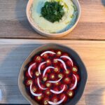 Serra Yılmaz Instagram - Evet son dönemde çok post yazmıyorum ama artık kayda değer lezzetleri ve güzellikleri yazmaya karar verdim. Karaköy’de eski Yolcu Salonunun yerine açılan Peninsula Otelin restoranı Gallada’ya davetliydik. Gallada bu mevsimde iki muhteşem terastan oluşuyor. En üstte bar altında restoran. Manzarayı görüyorsunuz, insan bakmaya doyamıyor. Fatih Tutak menusu yiyeceğimiz için de heyecanlıydık doğrusu. Enginar ve domates salatasıyla başladık, ikisi de çok leziz ve şaşırtıcıydı, zaten domatesler yemeğin sonuna dek soframızda kaldı arada dayanamayıp iki tane daha atıyorduk ağzımıza. Sonra biri yengeç biri karides dolu mantı damağımızı şenlendirdi. Siyah sarımsaklı fener balığının fotoğrafını bile çekemedik. Ama gelelim tatlılara : hem çok doyduğumuzdan hem şeker oranı yüksek tatlara uzak olduğumdan hem de sıkı bir “yuzusever” olduğumdan tabii ki yuzu karını seçtik! İşte bu tatlı bizi çocukluğumuza götürdü ve resmen sevindirdi! Kar yemiş iki kız çocuğu sevinciyle ayrıldık masamızdan! Şef Fatih Tutak’a ve bizi ağırlayan tüm Gallada ekibine çok teşekkür ederiz. Lezzetle kalın! @fatih_tutak @galladaistanbul #davet 🇮🇹 Siamo state invitate nel Ristorante Gallada sull’albergo Peninsula a Istanbul. La vista è grandiosa uno non vuole partire. Il menu è del chef doppio stellato Fatih Tutak ed è semplicemente squisito. Ne siamo partite con una gioia infantile visto il dolce che abbiamo mangiato: neve di yuzu!