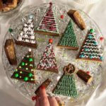 Veronika Danišová Instagram - Minule sme tu mali super odozvy na písané-statické recepty, tak skúsime ďaľší❤️ 🎄Kreatívne “cukroví” alebo nepečené STROMČEKY🎄…samozrejme ich môžete nakrájať aj ako malé stromčeky na jeden hryz🤤 Suroviny: 210g arašídové maslo hladké 100g praclíky (Mixit preclíky - perníkové koření) 140g vločky (Mixit creamy oats) 70g lieskové orechy (Mixit pražené líškové ořechy) 170g ryžový alebo kukuričný sirup alebo med 80g mletý hnedý cukor Postup: Cukor a sirup/med dáme spolu zahriať do hrnca a miešame až do úplného spojenia a jemného zabublania, následne pridáme arašídové maslo a všetko premiešame až do jednotnej hmoty. Praclíky rozmixujeme nahrubo a lieskové orechy nakrájame nahrubo. Vločky, orechy, praclíky spojíme a zalejeme rozohriatou tekutinou. Plech o veľkosti 20x20cm vystelieme pečiacim papierom a hmotu roztlačíme po celom obsahu plechu. Doporučujem pracovať v gumených rukaviciach. Pekne to zahladíme a dáme na chvíľku do chladničky cca 20min. Pripravíme polevu. Poleva: 180g čokoláda (70%) 100g arašidové maslo Všetko spolu rozohriať vo vodnej lázni a naliať na schladnutý základ. Následne vložiť do mrazáku na cca 25-30 min a krájať na trojuhelníky. POZOR nenechávajte to mraziť/chladiť príliš dlho, čokoláda by mohla praskať alebo by sa vám to potom porcovalo ohromne ťažko. Stačí zachladiť tak, aby bol vrch na dotyk pevný. Kresba: Klasická cukrová poleva 1 bielok 200g preosiaty práškový cukor cca 1PL citrónovej šťavy Všetko vymiešať šlahacím nástavcom do požadovanej tuhšej konzistencie, vložiť do sáčku a zdobiť. Zdobenie: praclíky @mix.it , cukrové guličky, sušené maliny @mix.it a čokoľvek čo vás napadne❤️ #nebesky #stromceky #pecemenebesky #sladkaspolupraca