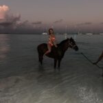 Victoria Spence Instagram - The most special morning 🥹🫶🏻 Every morning the race horses are taken to the beach at sunrise to roll in the sand, have a swim and get bathed. 🌅 We got talking to one of the guys and he asked if I wanted to get in, and next minute his hands were out ready to push me onto the horse😅 my heart was in my mouth at first, but it was the most precious experience! I’ll literally never forget it🥹 To top it off, he told me the horse was called Jerusalema after the song, which if you’ve been here a while, you’ll know my obsession with that song- one of my faves ever!🥲 I’ll remember this morning forever ❤️ @mikesingym can we get a horse?! #barbados#corememory