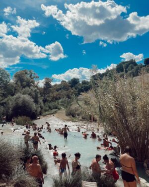 Allie Gonino Instagram - It’s not so easy to get to Saturnia, a small village in the middle of Toscana. Surrounded by rolling hills, olive tree farms, and vineyards nestled in deep valleys, is Le Cascade Di Saturnia. This is a sulfuric thermal spring where the water is as warm as a bath, and contains so many essential minerals. If you look behind me in the second photo, you can see the waterfalls that flow into the pools. I sat in meditation for nearly 40 minutes under one of the high pressure areas and allowed myself to just receive a deep, cathartic massage from Mother Nature. I can’t remember the last time I felt so relaxed and nurtured. Traversing the pools full of people takes a bit of balance and mindfulness, but once you’re in, you’re in. This moment was definitely worth the trip.