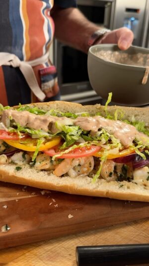 Andrew Zimmern Instagram - What if you made shrimp scampi... And then stuffed it in a torpedo roll, topped it with fresh lettuce, tomatoes, and onions, and drizzled it with a zesty remoulade sauce? 

That’s my Garlic Butter Shrimp Po’ Boy made with my @badiaspices Lemon & Shallots Seasoning. 

Don’t sleep on this one! Even if downing this massive sandwich creates some serious nap time. My suggestion is sharing. 

Pick up my entire Badia Spice line at at your local @krogerco, on andrewzimmern.com/spices, or on bodega.badiaspices.com. Full recipe is at the link in my bio, PLEASE try this one at home and tag me in the posts!