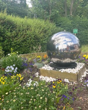 Anneka Rice Instagram - Oh my goodness. I went to Birkenhead, near Liverpool, today, to visit our Dementia Village, built on Challenge Anneka in 2022. It is flourishing. On a piece of wasteland a team of epic volunteers, builders, craftsmen, built an entire memory village - with pub, post office, record shop, cafe, bakers, cinema, bowling lawn, landscaped gardens! We worked in the pouring rain, in a recession, it was beyond stressful - but I thought my heart would burst, visiting it in the sunshine today, seeing what a difference it has made in this Wirral community. They now have over 400 volunteers helping out. The idea is that someone with dementia can wander safely round the village, dropping in on shops, listening to their favourite record, watching a film, having a singalong in the pub, doing whatever they want. It’s liberating for them and their loved ones because on every corner, sitting in the shops, offering them a cuppa in the cafe, there are carers to help them, chat to them, play bowls with them, sing with them. Each shop is curated to trigger memories. I went down a rabbit hole of memories seeing the Green Shield Stamps in the Post Office! IT IS BRILLIANT. I would love to see this rolled out across the UK. Well done @ageuk_wirral for having such vision 🩵🩵🩵 @age_uk #dementia @alzheimersresearchuk #village #ChallengeAnneka #charity #volunteers #community #joy @channel5_tv