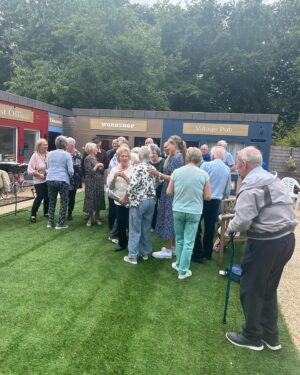 Anneka Rice Instagram - Oh my goodness. I went to Birkenhead, near Liverpool, today, to visit our Dementia Village, built on Challenge Anneka in 2022. It is flourishing. On a piece of wasteland a team of epic volunteers, builders, craftsmen, built an entire memory village - with pub, post office, record shop, cafe, bakers, cinema, bowling lawn, landscaped gardens! We worked in the pouring rain, in a recession, it was beyond stressful - but I thought my heart would burst, visiting it in the sunshine today, seeing what a difference it has made in this Wirral community. They now have over 400 volunteers helping out. The idea is that someone with dementia can wander safely round the village, dropping in on shops, listening to their favourite record, watching a film, having a singalong in the pub, doing whatever they want. It’s liberating for them and their loved ones because on every corner, sitting in the shops, offering them a cuppa in the cafe, there are carers to help them, chat to them, play bowls with them, sing with them. Each shop is curated to trigger memories. I went down a rabbit hole of memories seeing the Green Shield Stamps in the Post Office! IT IS BRILLIANT. I would love to see this rolled out across the UK. Well done @ageuk_wirral for having such vision 🩵🩵🩵 @age_uk #dementia @alzheimersresearchuk #village #ChallengeAnneka #charity #volunteers #community #joy @channel5_tv