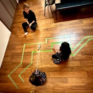 Atsushi Tamura Instagram - 娘たちがゲームを作ってみたいと言うので…小学生の頃に作ったことがあるゲームを３人で作ってプレイしてみました😃養生テープでクネクネの道を作って、ペットボトルに括り付けた紐を３人で協力しながら引っ張り道を進むゲーム、倒れたらスタートからやり直しって単純なルールですが、３人でケラケラ笑いながらプレイしました。

娘たちへ
自分たちで作ってみるという考えを持ち続けてください。きっとこの先の社会はどんどん便利なものが増えて、それを利用してれば満足いくし、特に困ることはないと思うけれど、あなたたちは今回ゲームを自分の力で作って楽しむことができたのだから、この先もきっとそれができるはず！あなたたちは作れるんだ！生み出すことができるんだ！ということを忘れないでね　　　パパより