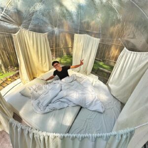 Aulion Instagram - TIDUR DALEM BALON ✨ Gimana rasanya? RIBET 🙃 Kesel banget ada moment gue lagi kebelet bgt, terus harus buka resleting balon ini yang macet. Ini pintunya ada 2 (untuk mencegah angin balonnya ke luar), pintunya model resleting gitu. 

Lokasinya di Sleman, Jogja 📍 karena di dataran tinggi, jadi malem dan paginya dingin gitu. Pemandangannya cakep, seger poooolllll, kayak lagi liburan banget (lah emang lagi liburan sih), teruss ada kolam renang & ayunan untuk chill & introspeksi diri. Harga semalem 600ribuan. Menurut kalian worth it gak?

Apakah gue akan nginep di sini lagi? Engga, karena pintunya ribet 🫠 dan ini yg indoor cuma kamar tidur & kamar mandi, jadi sisanya outdoor dan bakal bertemu keluarga kecil semut, serangga & kodok. Bukannya gue takut, tapi lebih ke.. risih aja sih sebenernya 😭🙏🏼