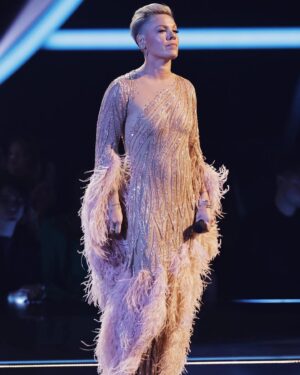 Bob Mackie Instagram - @pink wearing a nude gown, in soft rose gold, iridescent sequins and bugle beads with soft pink feathers at the @amas, for her Olivia Newton-John tribute performance. Swipe to see Bob Mackie’s original sketch for @cher’s 'Here We Go Again' Tour 
.
.
Costume made by @tricorneinc in NYC. Hand embroidery by Elizabeth Beading.
.
#pink #amas #cher #bobmackie mackiemagic #olivianewtonjohn