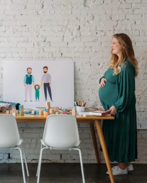 Brian Patrick Flynn Instagram - With only four weeks left, it seemed smart to dive into Swaddling and Wrapping 101 with our gestational carrier, Marissa, who’s documenting the entire surrogacy POV, process and science over at @thebellybud | Also, she’s a graphic designer by trade and designed the two dads art and the wooden midcentury building blocks if you swipe through. Also also: that’s a lifelike newborn doll named Evan nestled in the wrap to practice with, not an actual newborn baby, just in case you see it and are like wait I have a question how is there already a baby there. 📸 @kellychristinesutton @kellychristinephoto