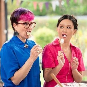 Cal Wilson Instagram - Pretty sure I got the @bakeoffau gig because of my natural elegance and grace. 
Tonight it’s CITRUS WEEK. Don’t be a sour puss, join us at 8.30 tonight on @foxtel and @binge.

#BakeOff #BakeOffAu #Bake #Baking #citrus #lifestyle #foxtel 

(Image one: the Bake Off shed. A brightly coloured Cal looks like she’s about to leap over also brightly coloured @natalie.tran. Cal has a leg flung out, and her two arms stretched ahead of her, like she’s auditioning to be a hood ornament.  Natalie is stylishly perched below, attempting to assist Cal’s flight. 
Image Two: Natalie and Cal stand at a bench, sampling marshmallows on a stick, Natalie looking cool and suave, Cal like she’s only just heard about this thing called eating, and she’s unconvinced)