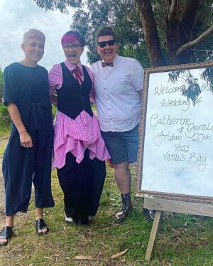 Cal Wilson Instagram - Congratulations @geraldinehickey and @cath_southgippslandcelebrant - your wedding was so filled with love and joy and wonderful people, and so absolutely you. So happy I got to be there to share it with you. 

(Image 1: 3 women standing together beaming. Cath, Bride 1, dressed in a gorgeous white beaded gown she made HERSELF, Geraldine Bride 2 in an incredible pink custom @reignerclothing suit adorned with embroidery and pearls, and a sassy veil. 
Cal is wearing a pink pinstriped @show_e_official shirt, and black @etalaustralia waistcoat and pants. This wasn’t meant to be a clothing crediting thing, I’ll stop now (except my nifty neck bow thing is courtesy @elenimstyling). 
Cal is holding a colourfully decorated Wedding album she made and foisted on the Brides. 

Image 2: 3 beaming women. Cal is in the middle with her arms around beloved mates @thegemmola and @theclairehooper. There’s a lot of great hair going on. 

Image 3: 3 Beaming women. Cal is in the middle with her arms around darling friends, Ranger Elle and @kirstywebeck. They’re standing next to a mirrored welcome to the wedding sign. Webeck’s boots are similarly mirror glaze.

Image 4: 2 women, one beaming, (the lovely @nic_minstergram) other one,  Cal, almost growling with the fury of how happy she is to be seeing Nicolette. They are hugging. Cal is winning)