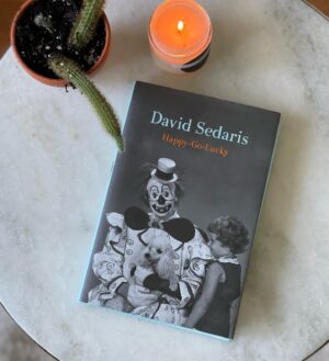 David Sedaris Instagram - HAPPY-GO-LUCKY, David’s new book, is finally here!*

Back when restaurant menus were still printed on paper, and wearing a mask—or not—was a decision made mostly on Halloween, David Sedaris spent his time doing normal things. As Happy-Go-Lucky opens, he is visiting muddy flea markets in Serbia, buying gummy worms to feed to ants, and telling his nonagenarian father wheelchair jokes.
 
But then the pandemic hits, and like so many others, he’s stuck in lockdown, unable to tour and read for audiences, the part of his work he loves most. To cope, he walks for miles through a nearly deserted city, smelling only his own breath. He vacuums his apartment twice a day, fails to hoard anything, and contemplates how sex workers and acupuncturists might be getting by during quarantine.
 
As the world gradually settles into a new reality, Sedaris too finds himself changed. His offer to fix a stranger’s teeth rebuffed, he straightens his own, and ventures into the world with new confidence. Newly orphaned, he considers what it means, in his seventh decade, no longer to be someone’s son. And back on the road, he discovers a battle-scarred America: people weary, storefronts empty or festooned with Help Wanted signs, walls painted with graffiti reflecting the contradictory messages of our time: Eat the Rich. Trump 2024. Black Lives Matter.
 
In Happy-Go-Lucky, David Sedaris once again captures what is most unexpected, hilarious, and poignant about these recent upheavals, personal and public, and expresses in precise language both the misanthropy and desire for connection that drive us all. If we must live in interesting times, there is no one better to chronicle them than the incomparable David Sedaris.

*oddly phallic cacti not included.