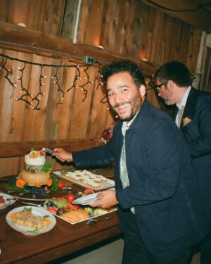 Ennis Esmer Instagram - I don’t think enough guests at the @evanyrosen-@james_hartnett wedding fully grasped or appreciated that this cake was made by stacking 4 wheels of increasingly decadent cheeses and adorning them with figs, flowers and grapes. Thank you @fudagraphy for capturing this moment that even @slorrin missed. #spoonwedding