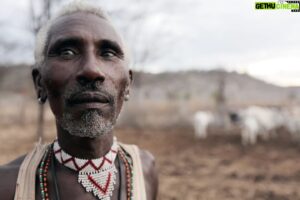 Hazen Audel Instagram - Lekeaora, was my host father when I was filming w/ the Samburu in Kenya. When we first met him we asked where his son was. We wanted to do a Primal Survivor National Geographic documentary exhibiting the lives of Samburu warriors. One of his 7 sons, (3 still alive) was living afar with his family's cattle as a warrior. Lekeaora & his wife had no idea where his son was- as warriors are typically gone from the age of 16 & return back at the age 23 years old- the age at which they are greatly respected for their accomplishments & are expected then to find a wife & get married. 
The search was on for his son. 
To accomplished the feat of finding them we had to search through leads after leads by other tribal families throughout a vast Samburu and Massai range of thousands of miles of desert, bush & mountains. 
The search was made more complicated as rumors spread quickly that we were looking for them because of criminal  accusations. So some people were giving out misleading information about their possible locations. 
We got there in the end. The three warriors were ecstatic to see us & to find out we wanted to show off their incredible lives to the world. 
When we found his son, he was with two other warriors taking care of about 80 cattle in remote dry valley. They were carrying the clothes on their backs, their weapons on hand or strapped onto their backs- machete, spear, club & machine gun. In the leather machete sheath was a large sharpened metal rod to do veterinary work & extract vicious thorns from their feet. They each also had chrome seiko digital watches, & small hand held makeup mirrors. (Warriors are heavily decorated & spend a lot of attention on their impressive appearance) The only other items were carried by a singular cow, a calabash container, and a special bow and arrow for extracting blood from the jugular vien of their cows. 
(While living and traveling with the warriors for two weeks we only had mik and blood to sustain ourselves)

Lekeaora was an energetic & kind man. He took me in and was eager to show me off as his newest family member. We mended lots of fence and spent our days carrying for his animals that were about. More in comments: