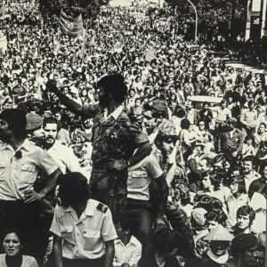 Isabel Abreu Instagram - 50 anos do 1° de Maio. Dia do trabalhador. Há uns anos comprei o @jornalexpresso, porque trazia uma crónica sobre o filme A Tristeza e Alegria na Vida das girafas que queria ler, uma entrevista com uma pessoa de quem gosto muito e uma reportagem sobre o 1° de maio de 1974. A beleza é que no meio desta multidão de pessoas, livres para gritarem e exigirem condições de trabalho dignas, melhores salários, horários de trabalho dignos, respeito pelos trabalhadores… uma quantidade de coisas que ainda hoje faz sentido exigirmos, vejo o meu pai. O meu pai que não tenho na minha vida há 38 anos. Sim, está lá no meio.  Reconheci o seu cabelo e os seus óculos. Sim, gritou. Sim, fez parte da luta. E ao lado da minha mãe. Ainda namoravam. Ainda eu não tinha nascido. Mas tinha nascido um país onde se podia gritar LIBERDADE, onde livremente podíamos exigir respeito. Obrigada a todas as pessoas que lutaram para termos o que temos. Não podemos deixar de lutar. Não se pode destruir o caminho que já se alcançou. E como eu não esqueci o meu pai e o reconheci e encontrei no meio deste mar de gente, não nos esqueçamos da história, das pessoas que tanto lutaram e encontremos e reconheçamos todas as razões do mundo para continuar a lutar por um mundo mais justo. Não se perca nunca a liberdade. Viva o 1° de Maio