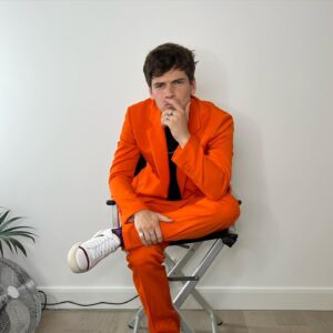 Jacob Dudman Instagram - Splash of colour 🍊 
For @fatenetflix press.

Styling: @ellalouisegaskell 
Make-up: @tonihowardmakeup 

Suit: @stellamccartney 
Chain: @tillysveaas 
T-shirt: @basicrights 
Shoes: @malonesouliers