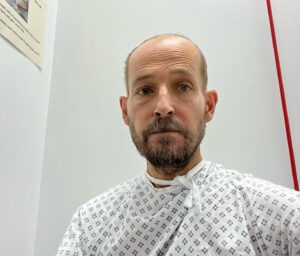 Jonnie Irwin Instagram - This is look of a man who’s not slept for 6 nights and awaiting a full body MRI scan of at least an hour. If you haven’t had one they’re claustrophobic and claustrophobic and omit loud random noises. Joy.
Take note on attempt of a jaunty not on my gown! I’m expecting to come out to news of India all out 195! ##alwaystrying #mri #livingwithcancer #nhs