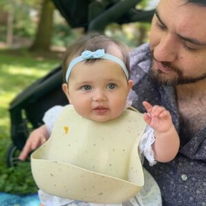 Katie Carpenter Instagram - we had a lovely picnic featuring my fave @hellyeahglutenfree treats 🍩 and FaceTiming with our mamas! 

Ryder came along too and isn’t 75 degrees the most PERFECT weather??! 

Cora is wearing a vintage dress made by my late grandma that I think I wore as a babe. 

And Kevin has been so sweet, he got me this beautiful birth stone necklace and printed out a poem that made me cry 🥹 (that we already spilled water on) 😂