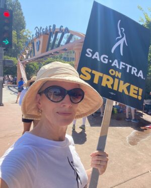 Kirsten Nelson Instagram - Week 2 for the #sagaftrastrike. 

Family affair back at Disney studios. Signs offering humor and levity in the scorching 100F valley heat. And f*** you, AMPTP. Bought some new trainers (yes, on SALE…) and my accountant already said yea, they ARE a write-off so THERE. I’ve got miles and miles now to go.

I don’t want it to be but it’s a marathon, not a sprint. Your move. #sagaftrastrong #wgastrong

P.S. and mad props to @blankcheckpod for our daughter’s favorite T!!