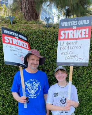Kirsten Nelson Instagram - Week 2 for the #sagaftrastrike. 

Family affair back at Disney studios. Signs offering humor and levity in the scorching 100F valley heat. And f*** you, AMPTP. Bought some new trainers (yes, on SALE…) and my accountant already said yea, they ARE a write-off so THERE. I’ve got miles and miles now to go.

I don’t want it to be but it’s a marathon, not a sprint. Your move. #sagaftrastrong #wgastrong

P.S. and mad props to @blankcheckpod for our daughter’s favorite T!!