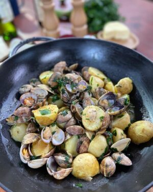 Laurent Mariotte Instagram - C’est la saison des pommes de terre primeur. J’ai rapporté de Noirmoutier cette idée pour les cuisiner alle Vongole!
À vous de jouer !🥔#pommesdeterreprimeurs 

Ingrédients (pour 4 pers.) :
800 g de pommes de terre nouvelles de Noirmoutier de taille moyenne
1 kg de palourdes
2 gousses d’ail
1/4 de botte de persil plat
50 g de beurre doux
2 cuil. à soupe d’huile d’olive
1 verre de vin blanc sec
Gros sel gris de Noirmoutier
Piment d’Espelette

Laissez tremper les palourdes dans une eau salée pendant 2 heures en changeant l’eau 3 fois afin d’ôter le sable.

Lavez les pommes de terre nouvelles. Placez dans une casserole d’eau froide salée et portez à ébullition. Faites cuire 20 min. 

Versez l’huile d’olive dans une large poêle munie d’un couvercle. Chauffez l’huile et ajoutez l’ail écrasé ainsi qu’un peu de piment d’Espelette. Laissez colorer légèrement puis ajoutez les palourdes égouttées. Remuez, ajoutez le vin blanc et couvrez. Laissez cuire pendant 2 à 3 minutes.

Lavez, équeutez et concassez le persil. 

Ajoutez le beurre en morceaux à vos palourdes ouvertes, le persil et mélangez.
Égouttez les pommes de terre, coupez-les en 2 ajoutez-les aux palourdes et mélangez. Dressez dans des assiettes légèrement creuses et dégustez aussitôt.