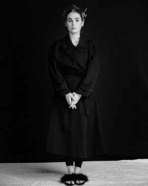Maiah Stewardson Instagram - w love 🧚🏼‍♂️🌶☁️

[ID image 1: a black and white portrait of Maiah’s side profile. They have their hair in two space buns and delicate flowers lining their jawline and hair. 
Image 2: a portrait of Maiah wearing an all black coat with fluffy black slippers. They are standing with their feet close together and hands clasped 
Image 3: Maiah looks back at the camera. Their hands are lightly clasped and shadows hit the side of their body and face].