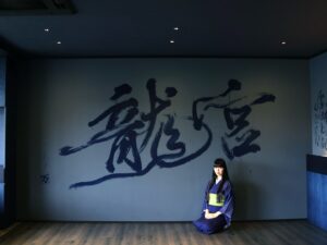 Mami Instagram - “龍宮”
2024,06,24, 佐賀県嬉野市・和楽園
@warakuen_chagokoro 

素晴らしい旅館の50周年を記念し、リニューアルされた客室の内装を担当いたしました。

「書く文字はお任せします」
と３代目よりオーダーをいただき、”日本三大美肌の湯” として知られる嬉野の泉質に癒されつつ、頭を振り絞って考えました。

左の壁「龍宮」は、
壁：艶消し藍色
インク：艶ありのネイビー
※これからベッドが来るので下のスペース空けてます💤

右の壁「亀ものがたり」は、
壁：艶消し藍色
インク：艶あり黒、艶ありネイビー、艶消し青緑

3色で書いた「亀ものがたり」は角度により見え方が変わり、まるで立体物のような平面作品を完成させることができました。

また、「龍宮」の文字を選んだ理由は以下。

--

①和楽園入り口にある池の亀たちが、竜宮城の乙姫を慕っていたという「亀ものがたり」のお話よりインスピレーションを受けた。

②竜宮城には水の神様がいる。和楽園はお茶と温泉を大切にしていて、どちらも水が鍵となる。

③竜宮城に赴いた者へは宝物が与えられる。私自身も、和楽園にて沢山の宝物となる時間を過ごさせていただいた。

④和楽園から徒歩圏内に豊玉姫（別名：乙姫）をお祀りする神社があり、書く前に参拝した。

〜三代目より個人的なエピソードも入れてOKと言われたので〜

⑤和楽園に伺った２日間、爽やかな雨が降っていて、龍神様が喜んでいるように感じた。

⑥自分自身の中にも新しい命がいて、水（羊水）がとても大切。龍年に子供を授かり出産することと、和楽園も今年50周年を期に新たな挑戦をするということで、「竜宮」を「龍宮」と表記した。

--

和楽園さん50周年おめでとうございます。
そしてお招きいただき、特別な時間を作っていただき、ありがとうございます！！！
またすぐに行きたい♨️🍵　

#和楽園 #嬉野温泉 #嬉野茶
#書道家万美 #mamimozi #Calligraf2ity