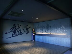 Mami Instagram - “龍宮”
2024,06,24, 佐賀県嬉野市・和楽園
@warakuen_chagokoro 

素晴らしい旅館の50周年を記念し、リニューアルされた客室の内装を担当いたしました。

「書く文字はお任せします」
と３代目よりオーダーをいただき、”日本三大美肌の湯” として知られる嬉野の泉質に癒されつつ、頭を振り絞って考えました。

左の壁「龍宮」は、
壁：艶消し藍色
インク：艶ありのネイビー
※これからベッドが来るので下のスペース空けてます💤

右の壁「亀ものがたり」は、
壁：艶消し藍色
インク：艶あり黒、艶ありネイビー、艶消し青緑

3色で書いた「亀ものがたり」は角度により見え方が変わり、まるで立体物のような平面作品を完成させることができました。

また、「龍宮」の文字を選んだ理由は以下。

--

①和楽園入り口にある池の亀たちが、竜宮城の乙姫を慕っていたという「亀ものがたり」のお話よりインスピレーションを受けた。

②竜宮城には水の神様がいる。和楽園はお茶と温泉を大切にしていて、どちらも水が鍵となる。

③竜宮城に赴いた者へは宝物が与えられる。私自身も、和楽園にて沢山の宝物となる時間を過ごさせていただいた。

④和楽園から徒歩圏内に豊玉姫（別名：乙姫）をお祀りする神社があり、書く前に参拝した。

〜三代目より個人的なエピソードも入れてOKと言われたので〜

⑤和楽園に伺った２日間、爽やかな雨が降っていて、龍神様が喜んでいるように感じた。

⑥自分自身の中にも新しい命がいて、水（羊水）がとても大切。龍年に子供を授かり出産することと、和楽園も今年50周年を期に新たな挑戦をするということで、「竜宮」を「龍宮」と表記した。

--

和楽園さん50周年おめでとうございます。
そしてお招きいただき、特別な時間を作っていただき、ありがとうございます！！！
またすぐに行きたい♨️🍵　

#和楽園 #嬉野温泉 #嬉野茶
#書道家万美 #mamimozi #Calligraf2ity