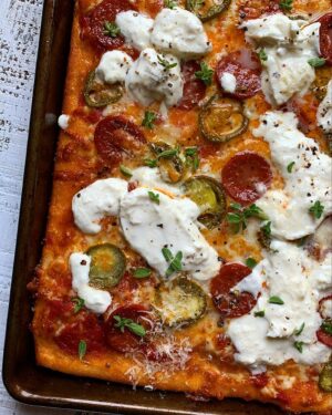 Megan Mitchell Instagram - This sheet pan pizza with burrata, jalapeño and pepperoni is low effort high reward. Definitely recommend making it this weekend.  Recipe👇🏼⁣
⁣
Ingredients:⁣
• Extra virgin olive oil, for drizzling⁣
• 13.58-ounce tube pizza dough⁣
• 3/4 cup jarred marinara/ pizza sauce⁣
• 1 1/2 cups thick-cut/shred mozzarella cheese⁣
• 1/2 cup pickled jalapeños⁣
• 2 ounces thick sliced pepperoni⁣
• Freshly cracked black pepper⁣
• 2 small balls or 1 large ball burrata cheese⁣
• 2 oregano sprigs⁣
⁣
Directions:⁣
• Preheat your oven to 450F⁣
• Drizzle 2 tbsp. of EVOO onto a 10x15 sheet tray. Unroll the pizza dough onto the sheet tray, pushing the edges to reach the corners and sides. If it bounces back let it sit for a few minutes and try again⁣
• Spread the sauce all over the pizza, leaving a 1/2-inch border, followed by the shredded cheese, sliced peppers and pepperoni. Finish with a drizzle of EVOO and a sprinkle of black pepper⁣
• Bake for 12-14 minutes or until the edges are golden brown and the top is bubbly⁣
• Remove and top with the burrata and oregano leaves. Cut and serve
