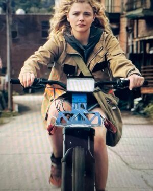 Michele Clapton Instagram - The Peripheral.
 Character Flynne Fisher 
Actor Chloë Grace Moretz 
Creating Flynne’s costumes set the tone for all the looks on the show. For the America near future looks we wanted to create a character that was relatable. She’s complicated, there’s a certain melancholy to her and she has pretty low self esteem, yet in other ways she is tough and resilient and a fighter. She’s a carer for her mum and she was close to her father who we discover has passed.
With all this in mind we started to design her looks. The oversized jacket was key, I decided that it was her Dads, (the script was changed to reflect this which was really cool) she wears it like he’s still protecting her, it comforts her and is also practical. Her trainers were part find/part build, Liz Crossman rebuilt them into high tops and added straps and colour..no small feat as we needed so many pairs. The denim shorts were also really particular in their cut, too short they looked too knowing, too long they felt like a statement.. we worked this all out in fittings with Chloë who was so engaged and brilliant.
The future London costume silhouette was based on this earlier look. I wanted it to be their interpretation of her, and I wanted Flynne to relate to it..The hood came from the jacket, the shorts became the Obi and the slim trousers reflected her bare legs. This look had to do so much and look cool of course!Texture was so important for it to look interesting on screen in all lights, Chloë also needed full movement in it to fight and allow for stunt pads..We made approximately 15 of this look to cover the show. The print I designed in house with Jack Beagley, Mel Carter (cutter extraordinaire) created the Jacket by draping on the stand, which was inspired, she really bought something very special to this piece. Verity Finney-Green created the beautiful fabric for the Obi. Emily Watson created and hand tooled the leather belt. So much of this look came together in the making of it and with Chloë’s endless passion for the character and patience in the fittings. We don’t even have a drawing of the final look, it can often happen this way.
Assistant Designer Susan Kulkarni