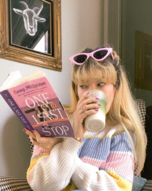 Michelle Grondine Instagram - book so good it’s got you like 🥨🪢⛓ 

just passed the halfway mark of One Last Stop by Casey McQuiston! does anyone else try to read the books they’re enjoying in small chunks so the story doesn’t end? i feel like the more i love a universe the longer i want to stay in it lately. and gosh, is this a fun book to exist in. 

btw this matcha latte with oat milk from @moongoatcoffee was perfection and this space is so cute. i want to transport this corner with the houndstooth arm chair with the goat oil painting into my home. (this is 💯 a milo the goat stan account 🐐). 

but truly, here i was like 🥨 trying to keep reading while drinking my latte hahaha. it’s not my fault this story makes me want to keep reading and reading and reading, not even stopping to drink my latte 😋🤩

really happy rn reading OLS, From Tokyo, With Love by Sarah Kuhn, and the audiobook for Six of Crows by Leigh Bardugo. next up i think i wanna start People We Meet On Vacation by Emily Henry, Arsenic and Adobo by Mia P. Manansala, and the audiobooks for Heiress, Apparently by Diana Ma, We Are Not Free by Traci Chee, and Loveboat, Taipei by Abigail Hing Wen.

q: what are some of your favorite audiobook performances?

i’ve been listening to more audiobooks whilst crocheting and am hungry for more! i rly love performances that include multiple actors (similar to a radio play) and when the authors themselves narrate their own stories. thanks in advance for all of your 🔥 recs, pals !!!

ps: the sweater, sunnies, and 🍄 earrings are all thrifted 🥰

pps: dropping my first set of azn films by azn creators recs tmrw for film friday 🎥