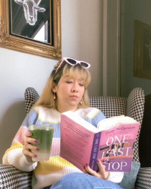 Michelle Grondine Instagram - book so good it’s got you like 🥨🪢⛓ 

just passed the halfway mark of One Last Stop by Casey McQuiston! does anyone else try to read the books they’re enjoying in small chunks so the story doesn’t end? i feel like the more i love a universe the longer i want to stay in it lately. and gosh, is this a fun book to exist in. 

btw this matcha latte with oat milk from @moongoatcoffee was perfection and this space is so cute. i want to transport this corner with the houndstooth arm chair with the goat oil painting into my home. (this is 💯 a milo the goat stan account 🐐). 

but truly, here i was like 🥨 trying to keep reading while drinking my latte hahaha. it’s not my fault this story makes me want to keep reading and reading and reading, not even stopping to drink my latte 😋🤩

really happy rn reading OLS, From Tokyo, With Love by Sarah Kuhn, and the audiobook for Six of Crows by Leigh Bardugo. next up i think i wanna start People We Meet On Vacation by Emily Henry, Arsenic and Adobo by Mia P. Manansala, and the audiobooks for Heiress, Apparently by Diana Ma, We Are Not Free by Traci Chee, and Loveboat, Taipei by Abigail Hing Wen.

q: what are some of your favorite audiobook performances?

i’ve been listening to more audiobooks whilst crocheting and am hungry for more! i rly love performances that include multiple actors (similar to a radio play) and when the authors themselves narrate their own stories. thanks in advance for all of your 🔥 recs, pals !!!

ps: the sweater, sunnies, and 🍄 earrings are all thrifted 🥰

pps: dropping my first set of azn films by azn creators recs tmrw for film friday 🎥