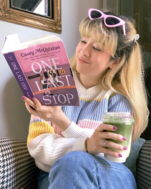 Michelle Grondine Instagram - book so good it’s got you like 🥨🪢⛓ 

just passed the halfway mark of One Last Stop by Casey McQuiston! does anyone else try to read the books they’re enjoying in small chunks so the story doesn’t end? i feel like the more i love a universe the longer i want to stay in it lately. and gosh, is this a fun book to exist in. 

btw this matcha latte with oat milk from @moongoatcoffee was perfection and this space is so cute. i want to transport this corner with the houndstooth arm chair with the goat oil painting into my home. (this is 💯 a milo the goat stan account 🐐). 

but truly, here i was like 🥨 trying to keep reading while drinking my latte hahaha. it’s not my fault this story makes me want to keep reading and reading and reading, not even stopping to drink my latte 😋🤩

really happy rn reading OLS, From Tokyo, With Love by Sarah Kuhn, and the audiobook for Six of Crows by Leigh Bardugo. next up i think i wanna start People We Meet On Vacation by Emily Henry, Arsenic and Adobo by Mia P. Manansala, and the audiobooks for Heiress, Apparently by Diana Ma, We Are Not Free by Traci Chee, and Loveboat, Taipei by Abigail Hing Wen.

q: what are some of your favorite audiobook performances?

i’ve been listening to more audiobooks whilst crocheting and am hungry for more! i rly love performances that include multiple actors (similar to a radio play) and when the authors themselves narrate their own stories. thanks in advance for all of your 🔥 recs, pals !!!

ps: the sweater, sunnies, and 🍄 earrings are all thrifted 🥰

pps: dropping my first set of azn films by azn creators recs tmrw for film friday 🎥