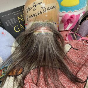 Neil Gaiman Instagram - Neil Gaiman’s Beard— for those who are curious about the process of making the beard, here are some fun facts! Initially, I made a mold of Neil’s face with a plastic bag, tape and sharpies so I could have the most accurate form to build on. I laid a fine theatrical translucent lace, pinned it into place, and tied single hairs on each ladder of the lace netting. This process can feel very monotonous and tedious, but it allowed me to place every single strand with intention to create the most natural blend of gray. This piece took about 20 hours to hand tie, because you have to tie the knots in a very specific direction to mimic the hair growth pattern— meaning I had to ventilate (knot) with the block in my lap, cradled by plushies instead of on a typical clamp stand that we would build a wig on. For reference, a fully hand tied wig takes about 60-100 hours depending on how specific you need to tie the growth pattern. After I was satisfied with the color blend, I did a very tiny roller set to achieve the texture of Neil’s actual facial hair, and barbered  it in the shape of the color reference photo. Dickens had some fun facial shapes over his life, and we went with the style that was contemporary to the first reading of a Christmas Carol in NYC IN 1867. 🎄🎅🏻