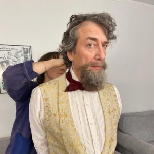 Neil Gaiman Instagram - Neil Gaiman’s Beard— for those who are curious about the process of making the beard, here are some fun facts! Initially, I made a mold of Neil’s face with a plastic bag, tape and sharpies so I could have the most accurate form to build on. I laid a fine theatrical translucent lace, pinned it into place, and tied single hairs on each ladder of the lace netting. This process can feel very monotonous and tedious, but it allowed me to place every single strand with intention to create the most natural blend of gray. This piece took about 20 hours to hand tie, because you have to tie the knots in a very specific direction to mimic the hair growth pattern— meaning I had to ventilate (knot) with the block in my lap, cradled by plushies instead of on a typical clamp stand that we would build a wig on. For reference, a fully hand tied wig takes about 60-100 hours depending on how specific you need to tie the growth pattern. After I was satisfied with the color blend, I did a very tiny roller set to achieve the texture of Neil’s actual facial hair, and barbered  it in the shape of the color reference photo. Dickens had some fun facial shapes over his life, and we went with the style that was contemporary to the first reading of a Christmas Carol in NYC IN 1867. 🎄🎅🏻