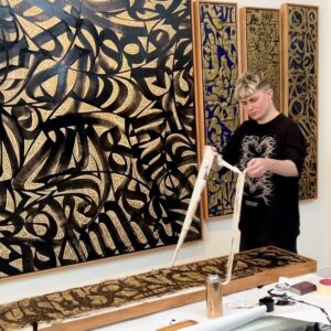 Pokras Lampas Instagram - Сегодня я начинаю рассказывать о своем проекте для Sharjah Calligraphy Biennial 2022 — которая в этом году проходит под темой "Elevation" и является 10-й по счету.

Мой проект — большое исследование современной каллиграфии, в котором представлено 27 работ под общим названием [ General Modern Calligraphy Styles & Scripts Research ], и аббревиатуой GMCSSR.

Подробнее о выставке я расскажу позже, а сейчас хочу представить одну из главных работ этой экспозиции — «Elevation: Traditions & Modern».

Работа написана в уникальной технике. Она создана при помощи эпоксидной чёрной краски. Это краска имеет свойство затвердевать через полтора часа после того, как смешиваются компоненты, и поэтому каллиграфия на двухметровом холсте пишется в очень интенсивной технике письма без права на ошибку, паузы или доработки потом. 

Нужно контролировать кисть, композицию, плотность краски на инструменте. И при этом понимать, что краска с каждой минутой становится всё более неподходящей для каллиграфии, это интересная проверка на мастерство и сосредоточеность.

При этом у работы есть ещё один слой - это очень тонкая выверенная золотая каллиграфия, которая писалась на протяжении недели в мастерской на Бали.

Процесс письма был для меня процессом медитации, поиском новых форм букв, которые вплетаются в пространство между чёрным и белым, между поверхностью самого полотна и каллиграфией, которую я создал в предыдущем этапе.

Не терпится поделиться с вами всей серией — а если вы в Арабских Эмиратах, то Биеннале можно посетить до 8 ноября в Sharjah Art Museum.