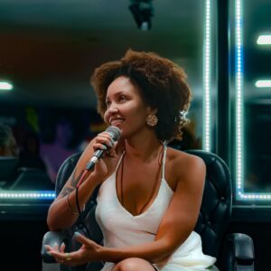 Sol Miranda Instagram - Foi uma experiência transformadora mediar a mesa de conversa sobre afeto na Yolo Love Party. Esse espaço de troca é um verdadeiro exercício de generosidade, onde ouvir o outro e suspender nossas certezas se reafirmam enquanto práticas essenciais em uma sociedade que frequentemente exige posicionamentos. 

Tivemos perspectivas diversas e enriquecedoras sobre o amor e o afeto com as contribuições de Renato Noguera, Camila Ribeiro do Projeto Ibejix, Jorge Mais Um do Projeto Papo de Baile, e a cantora e historiadora  Azula.

@noguera_oficial , em seu livro “Por Que Amamos?”, explora o amor como um ato coletivo e profundamente p0líT|c0. Ele afirma que “o amor é uma prática coletiva que envolve a construção de um mundo mais justo e igualitário”​ (Trechos Org)​. Noguera propõe que o amor vai além das emoções individuais e se estende à comunidade, desafiando-nos a repensar nossas relações de forma mais inclusiva e solidária.

Em plena comunhão com esse pensamento, o Projeto Ibejix, liderado por @camillaribeiror, centra-se na primeira infância a partir de uma perspectiva afrocentrada, enfatizando a importância do afeto e da identidade cultural no desenvolvimento das crianças negr4s. 

A conversa sobre masculinidades negr4s, trazida por @jorgemaisum ,reforçou como o amor e o cuidado são essenciais para desconstruir estereótipos e construir identidades mais saudáveis e positivas.

@azuladacordomar , com sua trajetória como mulher trans e artista, trouxe uma dimensão poderosa sobre como o amor e a aceitação são fundamentais para a luta por direitos e reconhecimento. Azula lembrou a todes da importância de um amor que acolhe e respeita as diferenças, promovendo a inclusão e a igualdade.

Discutir o amor sob essa ótica de organização e compreensão profunda é vital. O amor precisa ser entendido, exercido e cultivado para não ser confundido com paixão efêmera. Através do diálogo e da escuta, podemos construir relações mais autênticas e transformadoras.

Agradeço a todos os participantes pela riqueza das discussões e à equipe da Yolo por proporcionar um evento tão significativo. 

📸 : @odoro_guilherme