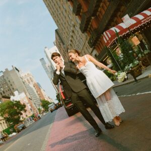 Barton Cowperthwaite Instagram - We were married in the Solarium next to the Piano Bar at the Hotel Chelsea. Choosing the Chelsea was an easy decision. It’s iconic, filled with art and history. I grew up on 22nd between 5th and 6th, and remember it in its late 90’s crumbling glory. The Solarium, small and perfect for our 35 guests, has a beautiful skylight running the length of the room. Decorated with plants and greenery, it was perfect as it was, requiring minimal decoration.

Our best friend Sammy (Bart’s best friend since birth) who knows us as individuals and as a couple better than anyone else, officiated the ceremony. It felt comfortable, relaxed, and unfussy. Our violinist played as we each walked down the aisle with our parents. The three of us stood in front of an arch I constructed from wooden dowels, tissue paper flowers from Etsy, Velcro, and hot glue. We were flanked by two bunches of my favorite Allium flowers. We each took a long moment to take in the space before our vows. We wanted to be as present as possible. 

After the ceremony, we had a champagne toast, and Bart’s brothers each said a few words. Our guests stayed for a cocktail hour while we left to do photos in our room. We left the Hotel Chelsea and went to the West Village with our photographers. Standing on a corner next to a tipped-over trash can for 15 minutes, trying to hail a cab, we were met with honks and cheers. It was a quintessential New York moment, a reminder that the city stops for no one.

We walked around the West Village, taking photos at all our favorite neighborhood spots. We stopped by Grove Apothecary to see our pharmacists, who have always taken such good care of us. We visited the Jane laundromat, where Bart has made friends with everyone who works there. We were all heartbroken when he got sick, but no one was as crushed as our friends at the laundromat. We dropped in at Casa Magazines, where Bart buys copies of the magazines he’s published in. This community is a part of our everyday lives. They’ve made our New York City feel like a close knit small town. Their kindness and care got us to the other side of a terrifying time, and we wanted to share a piece of the other side with them.