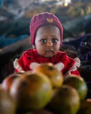 Dominic Arpin Instagram - La petite fille aux mangues. C’est de cette façon que je l’ai baptisée. Quelques jours avant d’aller gravir le Kilimandjaro, je suis allé visiter le marché de Moshi, en Tanzanie. Une expérience sensorielle déroutante avec tous ces bruits, ces odeurs, ces couleurs. Alors que je marchais à travers les allées, complètement subjugué par ce maelström, je l’ai aperçue, assise sagement sur un présentoir de fruits. La petite fille aux mangues. 🥭 Le moment a duré moins d’une minute mais ces yeux sont un des plus beaux souvenirs que je conserve de mon voyage!