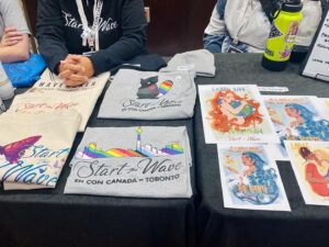 Dominique Provost-Chalkley Instagram - To all EhCon attendees… Please make sure to head by our @start_the_wave booth today for your final chance to get a STW Eco Merch item and support our organisation!!! 
You will meet some of our amazing team and can ask all the questions you may have about what we do. Have a beautiful day! 🦋💙🌈 #startthewave #ehconcananda