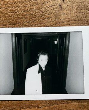 Emma D'Arcy Instagram - HotD LONDON ‘24 🪩⚜️📀

Club classics by @rosefordestudio and @canaku_ 
w a mouth full of gold by @bitter.000000 
  an arrow through the ear by @boucheron 
Hair my dad would be proud of by @jodytaylorhair 
and the face-i-wish-i-had by @phoebewalters 
Pics   joy by @tmayb 
Peace   love by @dobbscld   @dfm16 

#hotd 

[image description: A black and white polaroid photograph on a wooden surface. The photograph shows a slim, white non-binary person wearing to a two-tone, black and white, double-breasted suit. They wear a silky black shirt without a tie. Black and gold buttons on the blazer reflect the light. The pointed collar of the black shirt sticks out in front of the white half of the blazer.]