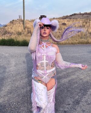Ilona Verley Instagram - “You were a mirage, you’re not really there”
🐎🐎🐎🐎
Inspired by @slayyyter & the cowboys music video!
🐎🐎🐎🐎
This look was originally made for me a few years ago by @connormccalden who did up the chaps/ bra & gloves for me when I was in Toronto for a few months and running out of outfits at the time!
I later made the hat and the bodysuit to go with it & @hauszuk helped me stone everything! 
🐎🐎🐎🐎
I’m so happy to have finally gotten to shoot this look & to do it with my incredible mom @sandiverley who took off a whole weekend to drive us up home to the canyon and literally camp until it was cool enough for us to drive to the ghost town to actually shoot… our one day trip turned into a 3 day adventure!
THANK YOU MOM!
🐎🐎🐎🐎
Hair was done for me the MORNING of by @the.girlfriendexperience
Also a big shout out to sheisbliss for helping me stone and get myself together that morning as well!
Hat was originally from @rockin_cowboy_clothing_company painted and transformed by me! (Reel coming soon on the DIY) 
Boots were from @onlymaker_shoes transformed by sheisbliss & myself! 
Earrings by @sadndn_ 
🐎🐎🐎🐎
I used to try to be so independent and do everything myself, but the last little bit, I’ve been giving up the perfection complex of wanting to do it all alone & it has helped me see that creating is not only easier but much more rewarding when you work with others, especially the people you LOVE!
The funny thing is to me the most perfect art has been the stuff I’ve done with friends… not the stuff I’ve done alone… (learning lesson for those struggling with giving up control / dealing with the typical artist perfection complex) 
🐎🐎🐎🐎
#cowgirl #cowgirlfashion #cowboyhat #purple #lavenderhair #humanhairwig #drag #dragqueen #purplemakeup #onlymaker #festivalfashion #ravegirl #ravegirls