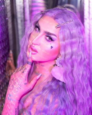 Ilona Verley Instagram - “Life of the party, but the party is finally over”
✨✨✨✨
HELLO INSTAGRAM!
I am so beyond excited to officially announce my new collaboration with @litcosmetics welcome to the stage PARTY GIRL glitter mix!
I wanted to create a shade that was true to my pastel brand & missing from my current glitter collection! 
Party Girl is a mix of different sized glitter to maximize sparkle with a lavender base ranging in holographic / indecent hues to tie into all the fun pastel colors I’m known for serving!
This is my absolute dream shade of glitter & I am looking forward to seeing all the looks you guys create with it! Make sure you hashtag #litcosmeticspartygirl so I can find all your fabulous serves!
✨✨✨✨
PS!!!
Use code ilonaverley-lit20 to save 20% off your entire order when you check out in the @litcosmetics website!!!
✨✨✨✨
Huge thank you to Jodie and everyone at Lit for always supporting my art and showcasing my talent long before I ever made it on tv! 
LOVE YALL SO MUCH!
✨✨✨✨
Couldn’t have put this project together with out the following fabulous friends! So if you like this look and these photos please show some love to the following::::
Photos @megsgiallo 
PARTY GIRL logo also by Meg!
Beaded earrings by @sadndn_ 
Assisted by @theevascarlett 
Big thank you to @numberscabaret for letting us in to shoot in their fab space!
Hair colored and styled by me! 
✨✨✨✨
#drag #instadrag #purplemakeup #purpleglitter #litcosmetics #partygirl #humanhairwig #crimpedhair #trans #browlamination #ilonaverley #canadasdragrace
