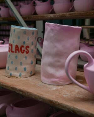 Joe Lycett Instagram - Back in October last year I went along to @duchesschina1888 in Stoke-on-Trent to see how they were getting on with the Slags Vase. It’s a very special sprawling place, steeped in history and so much love for ceramics and their production. I was fortune to meet Gordon who is their master modeller, whose job it was to measure up my original piece-of-shit design and recreate it in bone china. I’d like to apologise to Gordon for making him stoop so low as to recreate my vase. I also got to see their production line and some of the other work they do for the royals, amongst others, and make a mug, which I’m pretty sure I watched someone immediately put into a bin. 

It was a total delight working with Gordon, Jason and the team on this project, all beautifully coordinated by @theymadethistagram 

The limited edition vases (only 250 made) go on sale to my mailing list tomorrow morning and all the money I make from the sales will go to @artsemergency. Sign up at joelycett.com