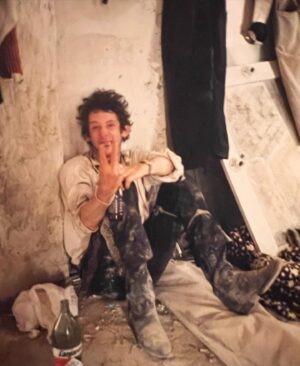 Xander Berkeley Instagram - RIP Shane MacGowan🙏❤️‍🩹 I feel so lucky to have gotten to know the enigma himself. Self destructive as anyone I’ve ever known, and more brilliant than most can imagine. Infused with Spirits of all kinds, Alcohol, the Holy Ghost and the ghostly spirit of Federico Garcia Lorca. Punk poet for the ages. Shane shambled down from the mountainside behind us there, one dawn when Joe Strummer and I had camped out on set to escape the chaos of the fiesta surrounding our hotel in Almeria. Sergio Leone’s old sets, dubbed Little Hollywood for all the Spaghetti Westerns shot there. As the sun crept up over the Andalusian hillsides,  painting the desert orange, down came Shane (still sporting his spurs and Mariachi outfit from filming the day before) prophetically proclaiming to us, down there in our #sleeping bags, “He’s out there! Garcia Lorca, mates! He’s out there!  Shane was deeply superstitious about me reading gruesome passages from the bible during breaks in filming. The second shot, for those still reading, was one I took to capture his revulsion of the sacrilege my character represented. He would ward me off with the V as if holding a cross up to a vampire, muttering, “Preacher… Evil…”. 
(A la ‘get thee back Satan’). Once when the two of us wrapped early, a cab took us back to the hotel, and I got him to sing ‘And the Band Played Waltzing Matilda’. Brought me to tears, which I hid, looking out the cab’s window. He stopped just short of the end, suddenly embarrassed and vulnerable for singing to some guy in a taxi. I was shocked he had consented in the first place, and I’ll be forever grateful that he did.  His voice was ragged and rough, but like the lyrics he wrote, he plumbed a depth of authenticity, that was pure and rare and will remain increasingly so as time passes. Glad we all had him for as long as we did, and have him with us still. Cheers, 🍻 to Shane MacGowan.