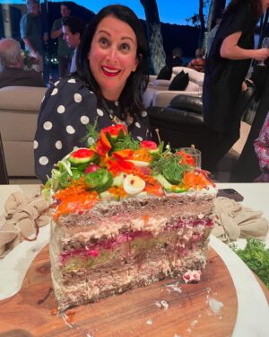 Annabel Crabb Instagram - Beautiful birthday celebration this weekend for my lovely friend @fionahughes3, a warm hearted, modest, funny, super competent general delight of a person. Also does not like sweet things so an intriguing birthday cake challenge. This one, concocted in collaboration with @glamgwenblake and modeled on the Swedish concept of Smorgastorte (or sandwich cake, and yes there are many umlauts and whatchamacallits missing from my reference) involves several large miche loaves from @goodwoodbakeshop from which rounds of bread were extracted like those arctic ice plug things, and layered with:
Salmon rillettes (hot smoked)
Zucchini and dill frittata
Beetroot pate
Tarama whipped w cream cheese.
Toppers: Cucumber ribbons and carved flowers, quail eggs, radish flowers, caper berries, horseradish and dill cream, pink pepper corns, salmon roe, candied baby beets, gone-to-seed herbs and nasturtium flowers from our primary school’s kitchen garden (stolen under cover of Book Week), also smoked salmon.
Thank you to our Scandi friends for being such sickoes as to normalise cakes made of fish. Also please enjoy my teenage son’s highly skeptical response on having the concept outlined.
Most importantly: Happy birthday to a good, good woman. ❤️ 
(And as usual thanks to @mr_stephenblake for photography, well the good photos anyway)